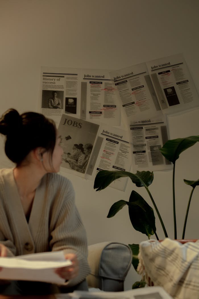 Mastering the First Impression: Your intriguing post title goes here A woman in a cozy setting reviews job listings on a wall, exuding a thoughtful mood.